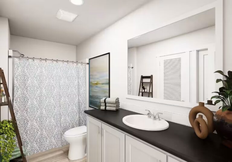 White bathroom with dark vanity countertop, oval sink, large mirror, and patterned shower curtain.