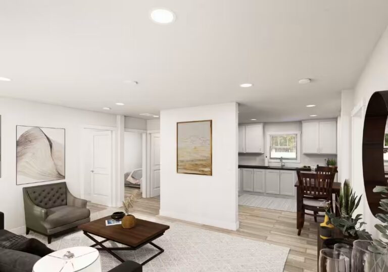 Bright open-concept living room with gray armchair, coffee table, and white kitchen with island