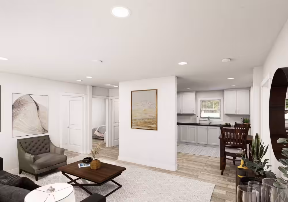 Bright open-concept living room with gray armchair, coffee table, and white kitchen with island