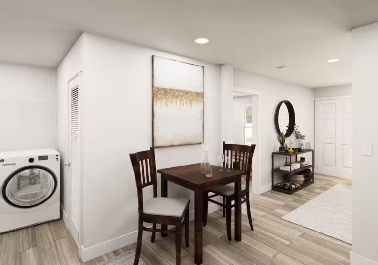 Small wood dining table with two chairs, wall art, washer, and hallway with round mirror.