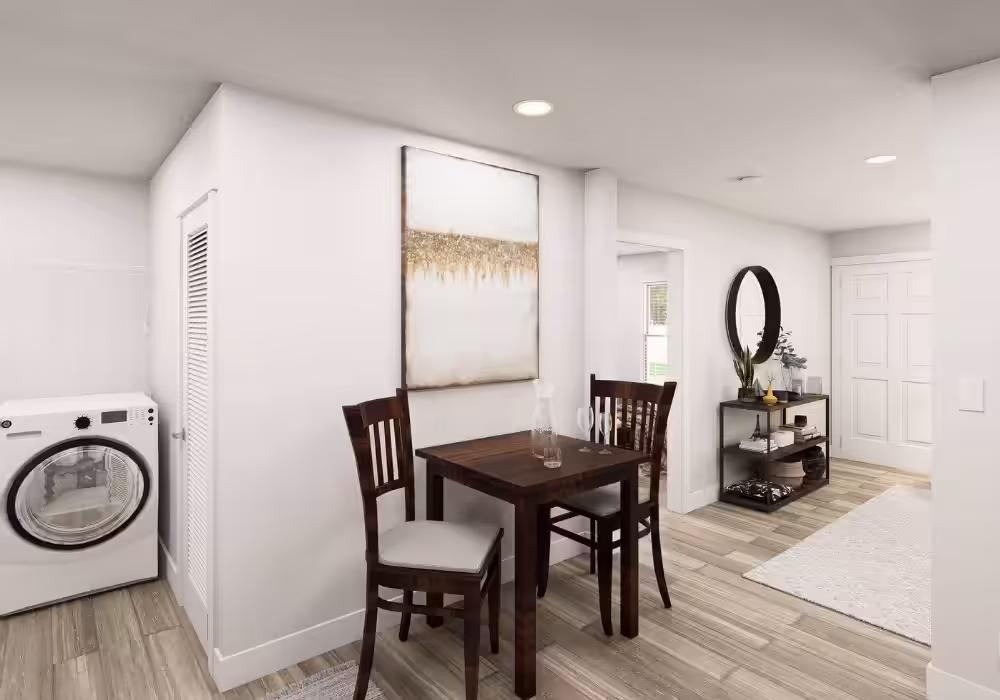 Small wood dining table with two chairs, wall art, washer, and hallway with round mirror.