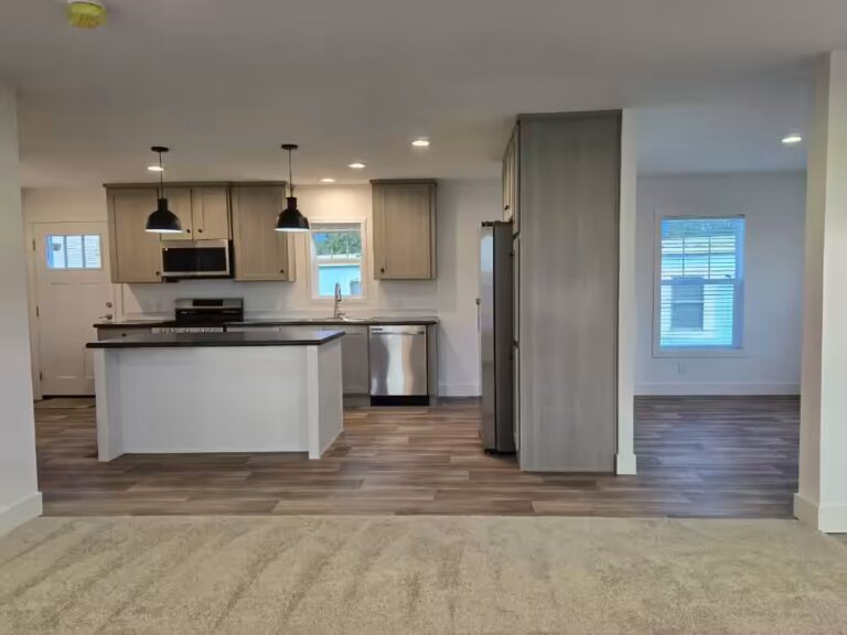 Open kitchen with white island, gray cabinets, pendant lights and stainless appliances