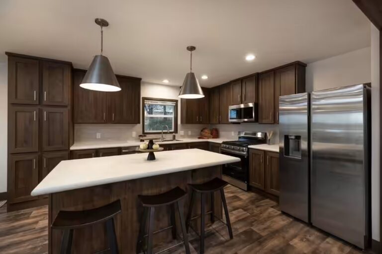 Modern kitchen with dark wood cabinets, white island with stools, and stainless steel appliances