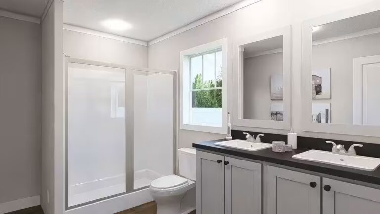 Bathroom with glass-enclosed shower, toilet, and double-sink vanity with mirrors above.