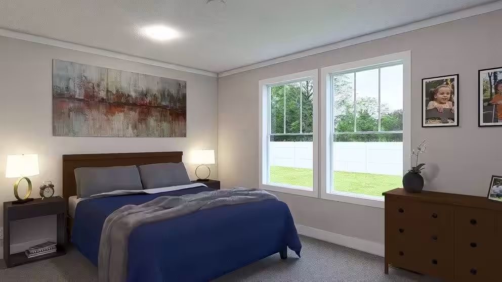 Bedroom with blue bed, table lamps, abstract art, and windows overlooking a fenced green yard.
