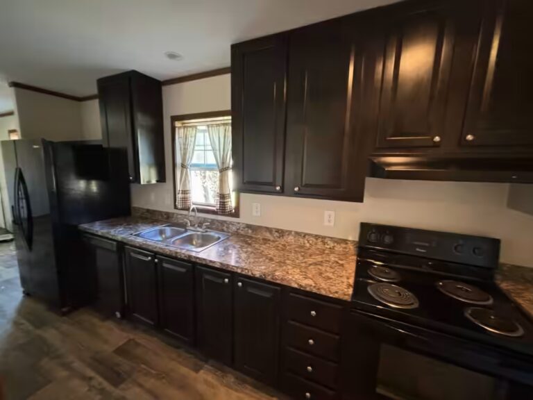 Kitchen with dark cabinets, granite countertops, black appliances, and window over double sink