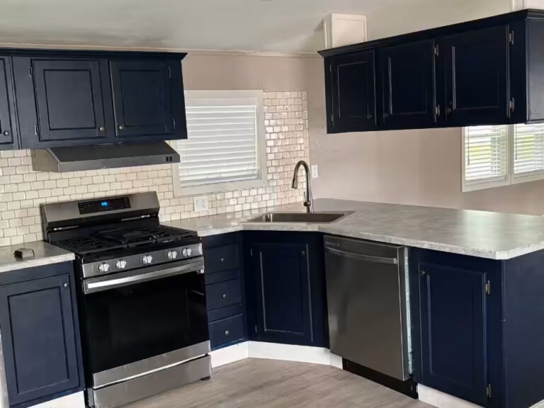 Navy blue kitchen with white subway tile backsplash, stainless gas stove, dishwasher, and marble countertops.